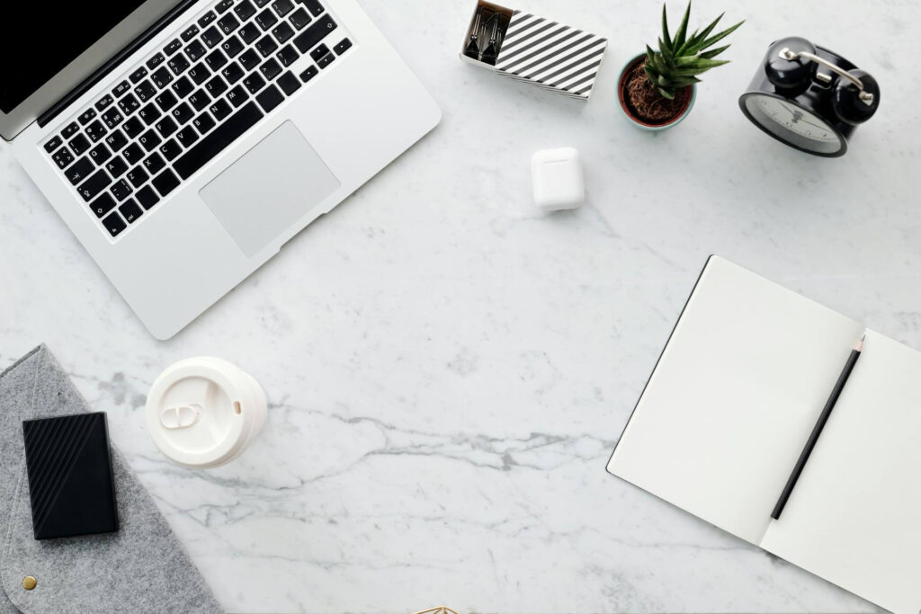 Minimalistinen työpöytä läppärillä ja muistikirjalla CRM-työskentelyyn