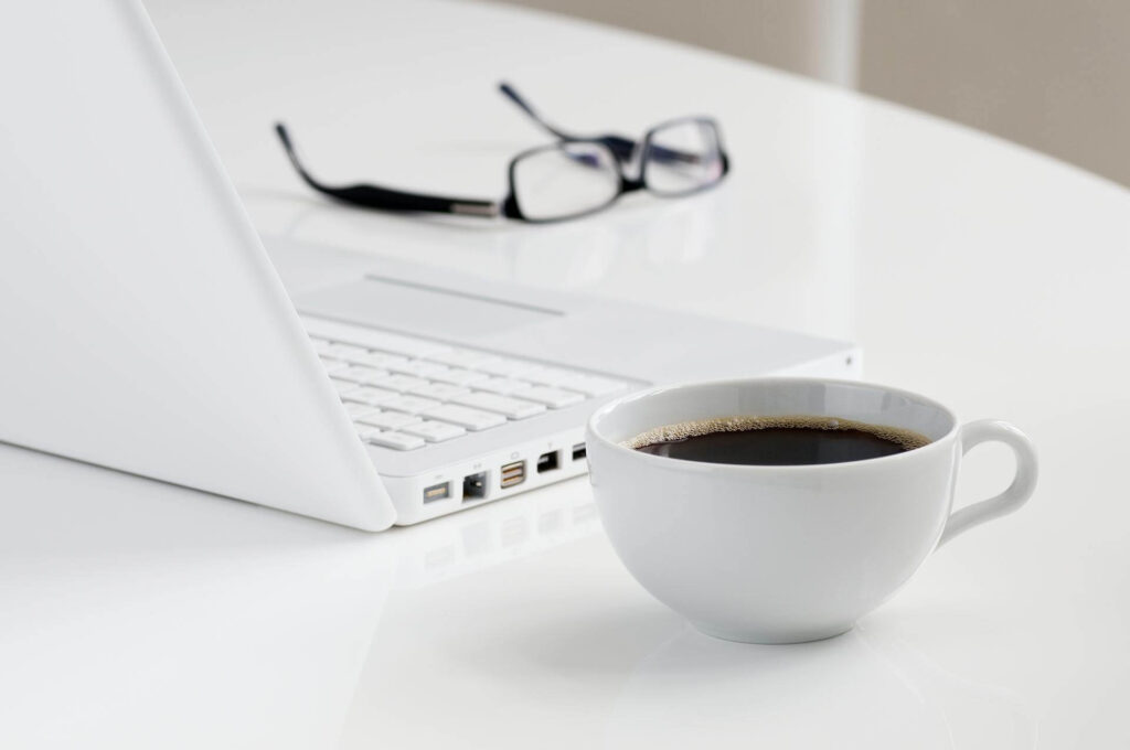 Pienyrittäjä työskentelee läppärillä kahvikupin kanssa